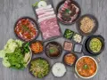 Obfity zestaw do korean bbq: surowe i marynowane mięso, kimchi, sałatki, ryż i dodatki.