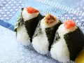Trzy onigiri z ryżem, zawinięte w nori, z łososiem, tuńczykiem i ikrą na wierzchu. Idealne na przekąskę.