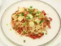 Smażony makaron Chow Mein z tofu, papryką i szczypiorkiem na talerzu.