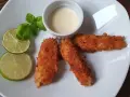 Chrupiąca ryba w panko, podana z sosem i limonką, wygląda apetycznie.