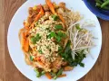 Pyszny Pad Thai z kurczakiem, warzywami i orzeszkami ziemnymi, polany aromatycznym sosem do Pad Thai.