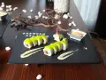 Dwa rzędy sushi z zielonym ikrą, podane z sosem i imbirem. Idealny sposób, jak podawać sushi na eleganckim talerzu.