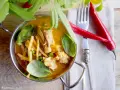 Aromatyczne czerwone curry z kurczakiem, bambusem i groszkiem, ozdobione świeżą bazylią i papryczkami chili.