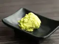 Zielona pasta wasabi na czarnej, kwadratowej miseczce. Zastanawiasz się wasabi co to? To ostry japoński chrzan.