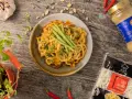 Udon co to? Makaron udon w kremowym sosie z orzeszkami ziemnymi i ogórkiem, obok paczka makaronu i tahini.