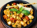Kawałki kurczaka w sosie z papryką i ziołami, ozdobione listkami bazylii i paluszkami grissini. Danie przypomina egzotyczne jungle curry.