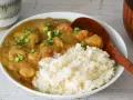 Pyszne japońskie curry z kurczakiem i warzywami, podane z ryżem i posypane szczypiorkiem.