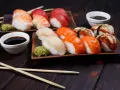 Wyśmienite japońskie sushi: nigiri z łososiem, rybą maślaną i krewetką, podane z wasabi i sosem sojowym.