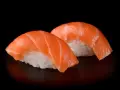 Dwa kawałki sushi z łososiem, idealna ryba do sushi, na czarnym tle.