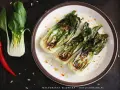 Grillowany pak choi z nasionami słonecznika i papryczką chili na talerzu.