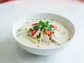 Aromaticzna zupa tom kha z kurczakiem, ozdobiona kolendrą, chili i trawą cytrynową.