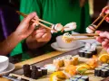 Ręce trzymają pałeczki, jedząc sushi. To smakowita uczta, która odzwierciedla japońskie tradycje kulinarne.