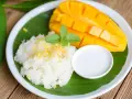 Pyszny mango sticky rice: ryż kleisty z kawałkami mango, polany mleczkiem kokosowym, udekorowany miętą.