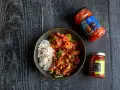 Miseczka ryżu z kurczakiem w sosie i kimchi, obok słoiczki z kimchi i pastą chili.