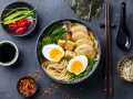A miseczce aromatycznego ramenu z tofu, jajkiem na pół, kurczakiem i zieloną cebulką. Obok sos sojowy, chili i nori.