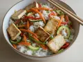 Miseczka ryżu z warzywami i tofu, obok pałeczki do sushi. Idealne danie, by nauczyć się, jak trzymać pałeczki do sushi.