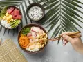 Dwie miski z pysznym sushi: jedna z tuńczykiem, awokado i ogórkiem, druga z krewetkami, fasolką i warzywami.