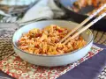 Miseczka pełna aromatycznego nasi goreng z warzywami i kawałkami mięsa, gotowa do jedzenia pałeczkami.