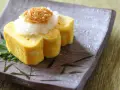 Roladki tamago z tartą rzodkwią i grzybami enoki na talerzu z motywem bambusa.