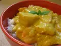Miseczka ryżu z kurczakiem w kremowym sosie z curry, ozdobiona listkiem mięty.