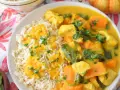 Aromatyczny kurczak curry z dynią i mlekiem kokosowym, podany z ryżem i posypany natką pietruszki.
