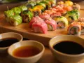 Kolorowe rolki sushi na desce, gotowe do zanurzenia w aromatycznych sosach.