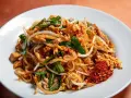 Pyszny pad thai z ryżowym makaronem, kiełkami, orzeszkami i chili. Idealny makaron do pad thai to cienki, płaski ryżowy.