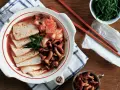 Pyszne kimchi jjigae z tofu i grzybami, podane z zieloną cebulką.