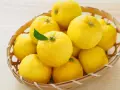 Kosz pełen żółtych owoców yuzu. To cytrusy o wyrazistym aromacie, często używane w kuchni azjatyckiej.