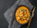 Aksamitne tajskie curry z krewetkami, podane w garnuszku z pałeczkami.