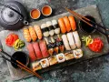 Zestaw sushi: nigiri z łososiem, krewetkami, tuńczykiem, węgorzem i rolki. Obok czajniczek, miseczki z herbatą i sos sojowy. Tak jedzą japończycy.