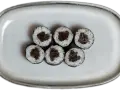Sześć kawałków sushi z ryżem i ciemnym nadzieniem na szarej tacy.