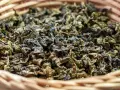 Suszone liście herbaty gunpowder w wiklinowym koszyku. Odkryj jej niezwykłe właściwości!