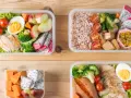 Kolorowe pojemniki z jedzeniem, idealne na japońskie bento przepis: kurczak, ryż, warzywa i owoce.
