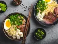 Pyszny ramen wołowy przepis: makaron, plastry mięsa, jajko, tofu, szczypiorek i papryczki jalapeño.