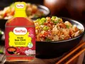 Butelka słodkiego sosu chili TaoTao obok miski ryżu po azjatycku. Idealny do mięs, kanapek, parówek.