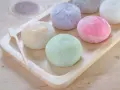Kolorowe mochi, czyli japońskie ciastka ryżowe, na drewnianej tacy. Zastanawiasz się mochi co to? To pyszna, miękka przekąska!