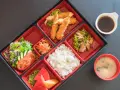 Japoński obiad w bento: smażone krewetki, ryż, sałatka, owoce i zupa miso.