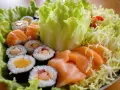 Talerz sushi z łososiem i warzywami. Jaka sałata do sushi? Ta chrupiąca, zielona sałata lodowa stanowi idealną bazę.
