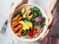 Pyszny bowl z kaszą, pieczonym batatem, awokado, tofu i czerwoną cebulą, polany pikantnym sosem do bowla.