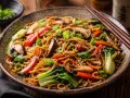 Makarony azjatyckie rodzaje: pyszne danie z makaronem, grzybami shiitake, papryką, bok choy i szczypiorkiem, posypane sezamem.
