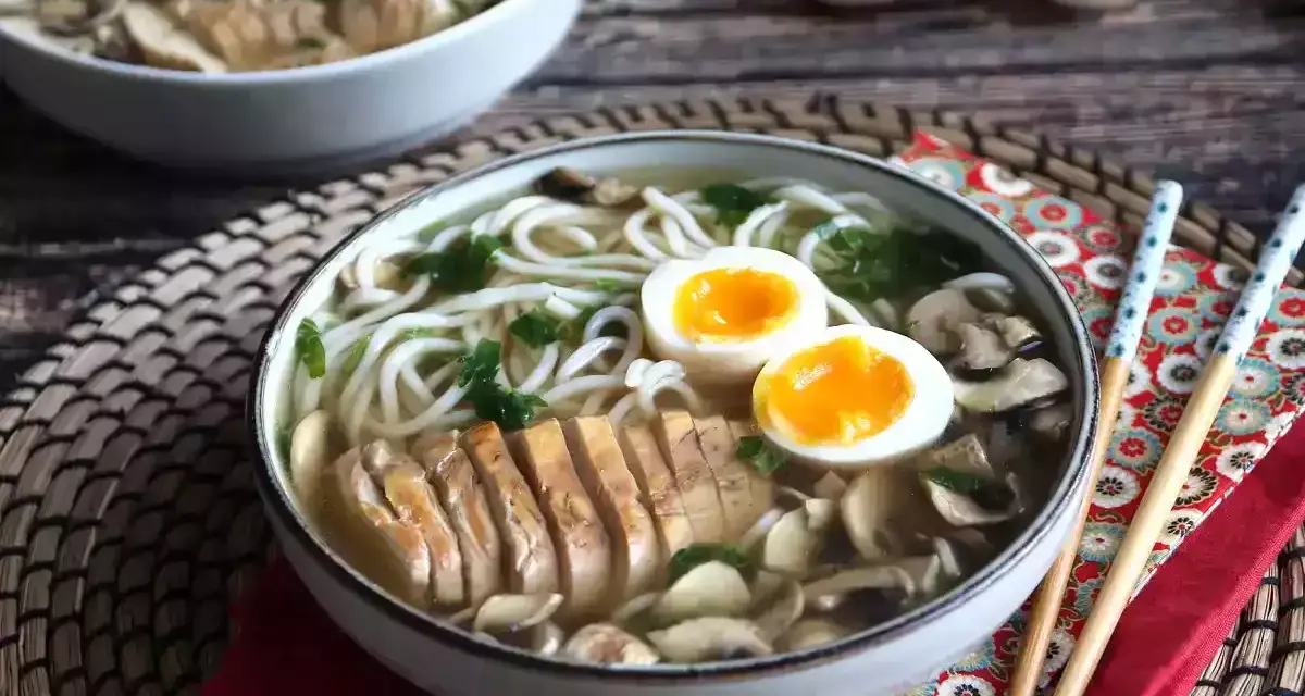 Pyszne ramen z kurczakiem, jajkiem na pół i grzybami. Aromatyczny bulion i delikatny kurczak tworzą idealne danie.