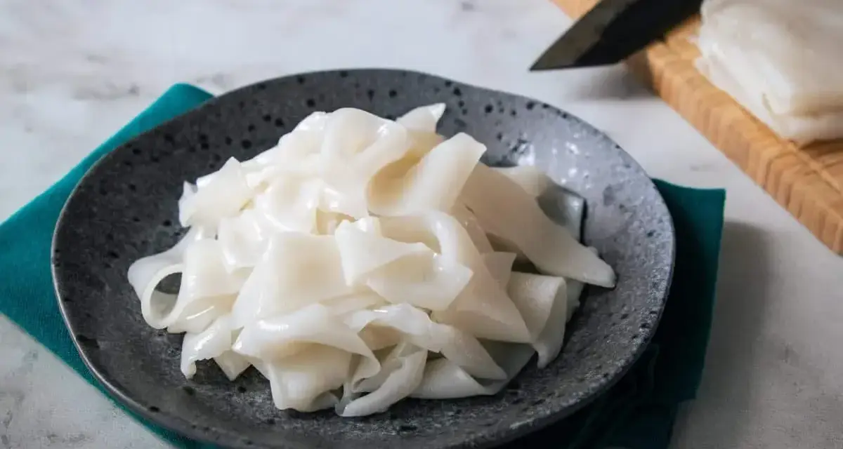 Płaski, biały makaron ryżowy na talerzu, gotowy do przygotowania pysznych dań. Szukasz inspiracji? Sprawdź makaron vermicelli przepisy!