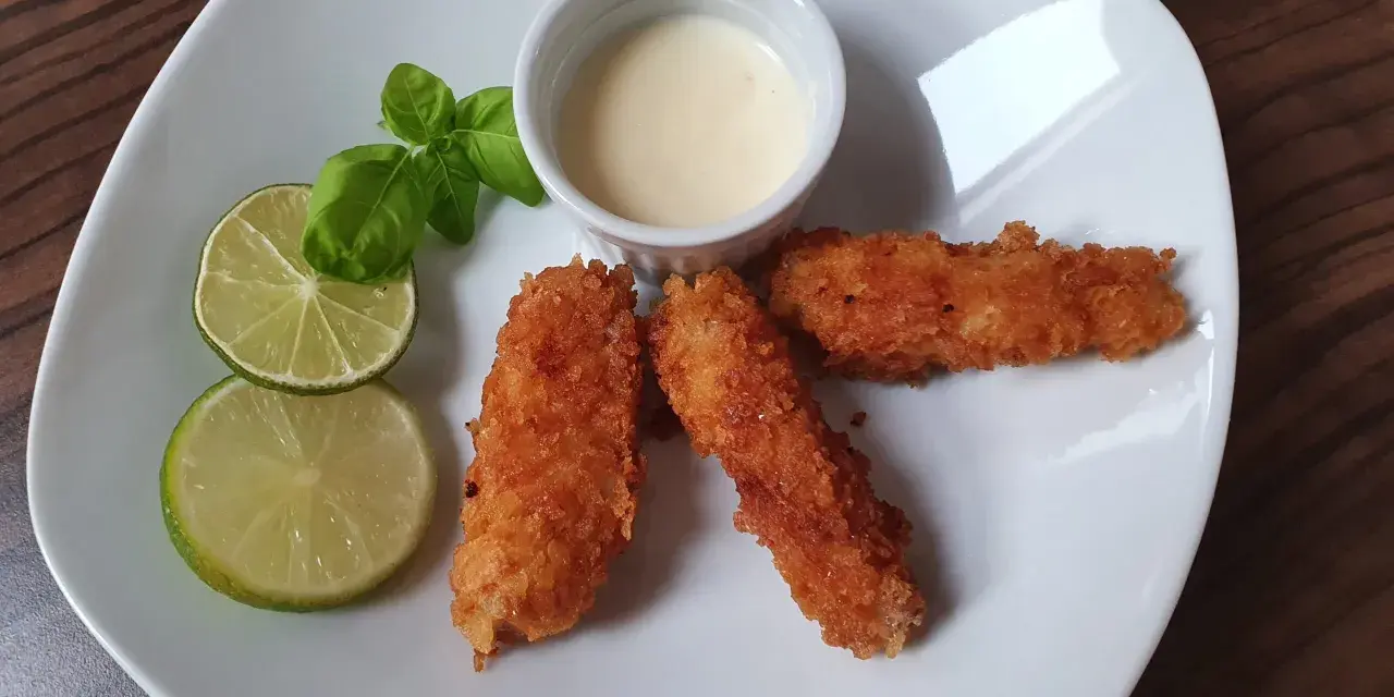 Chrupiąca ryba w panko, podana z sosem i limonką, wygląda apetycznie.