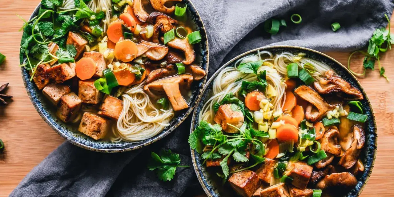 Dwie miski aromatycznego bulionu z makaronem, grzybami, marchewką i kostkami pysznego tofu na kolację.