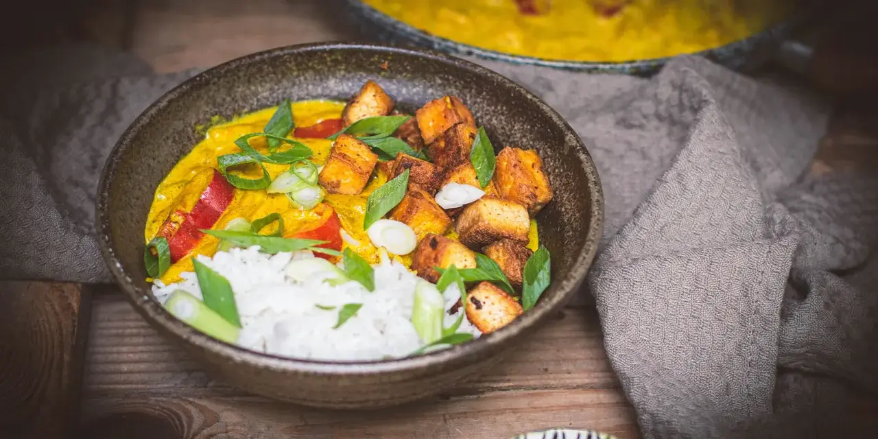 Aksamitne mango curry z ryżem, chrupiącym tofu i świeżą bazylią. Danie prezentuje się apetycznie.