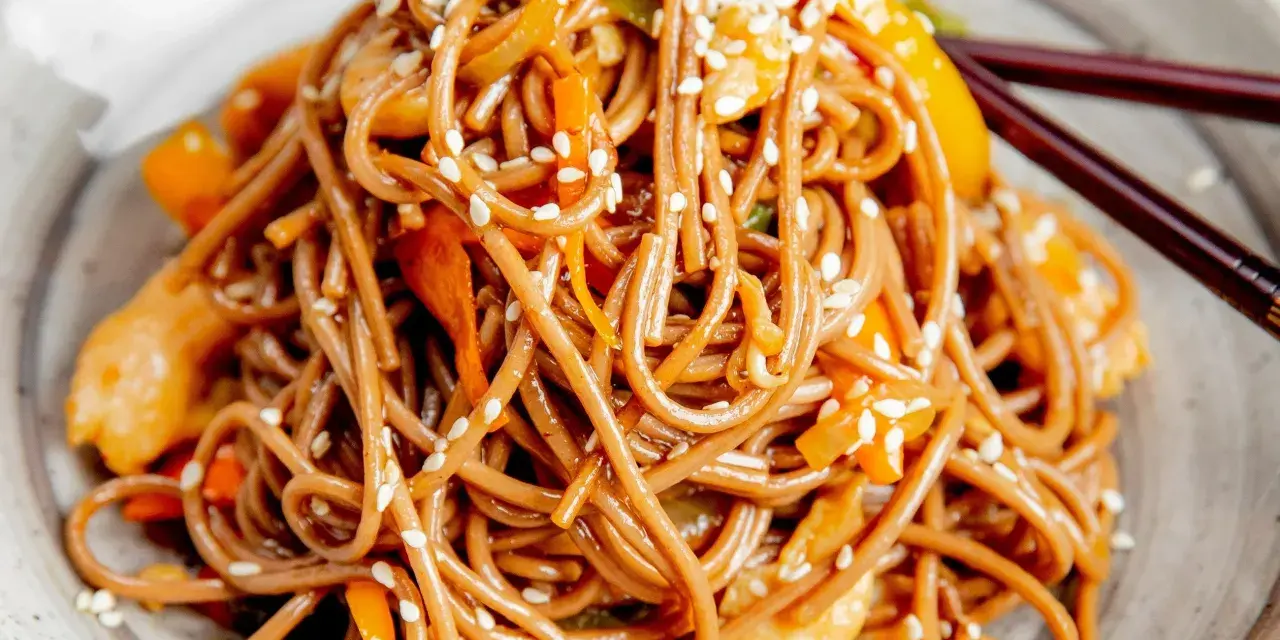 Soba z kurczakiem i warzywami, posypana sezamem. Pyszny przepis na soba, idealny na szybki obiad.