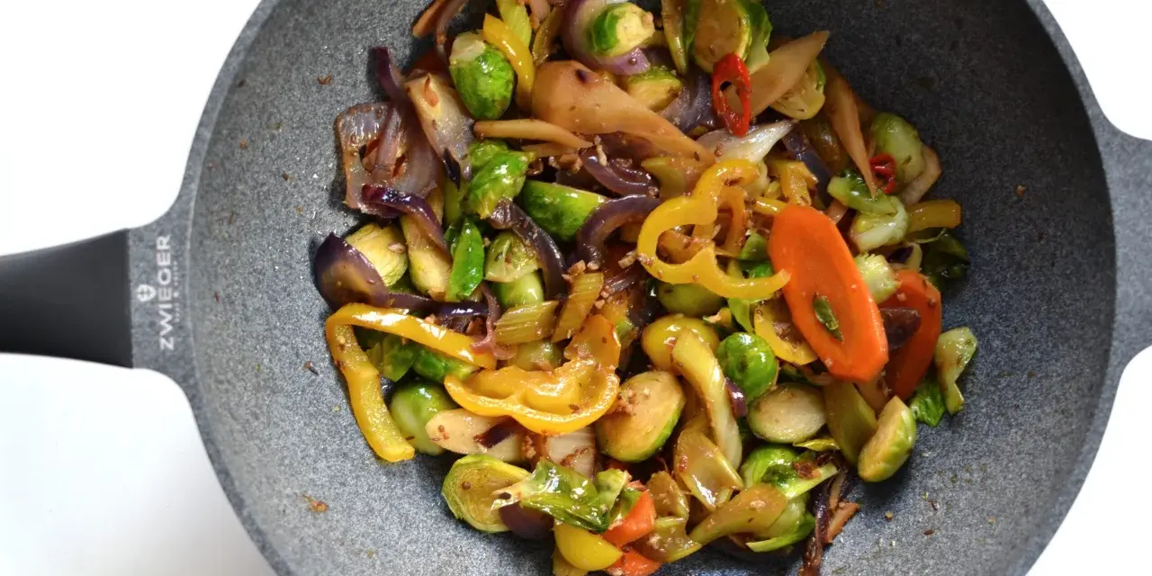 Kolorowe warzywa stir fry z brukselką, papryką i marchewką na patelni.
