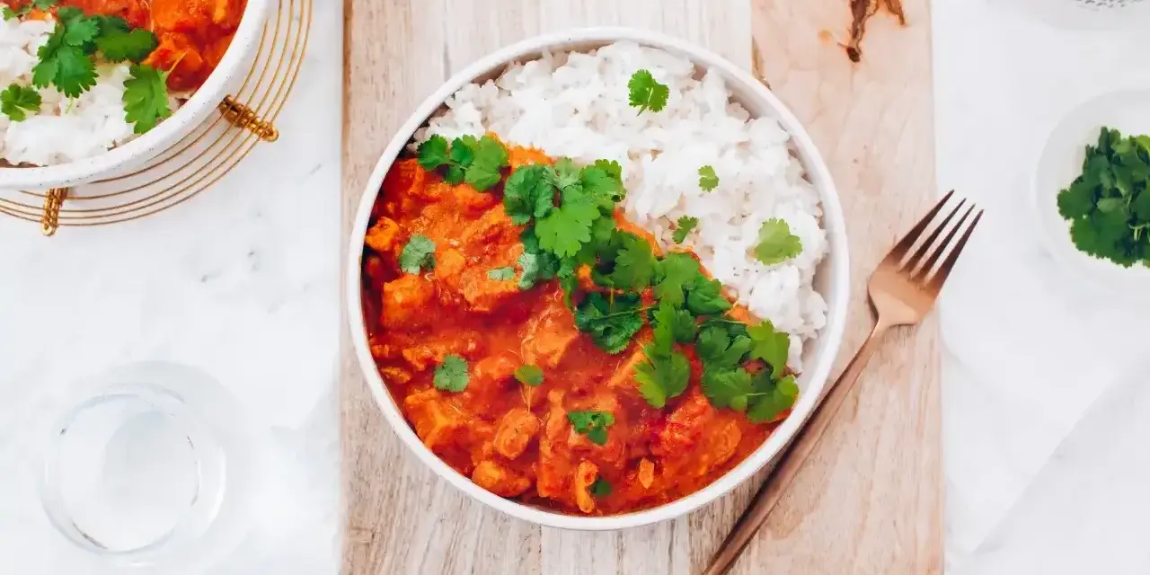 Aksamitny kurczak w czerwonym curry, podany z ryżem i świeżą kolendrą. Idealny na rozgrzewający posiłek.