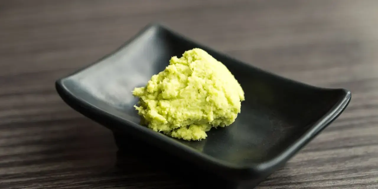 Zielona pasta wasabi na czarnej, kwadratowej miseczce. Zastanawiasz się wasabi co to? To ostry japoński chrzan.